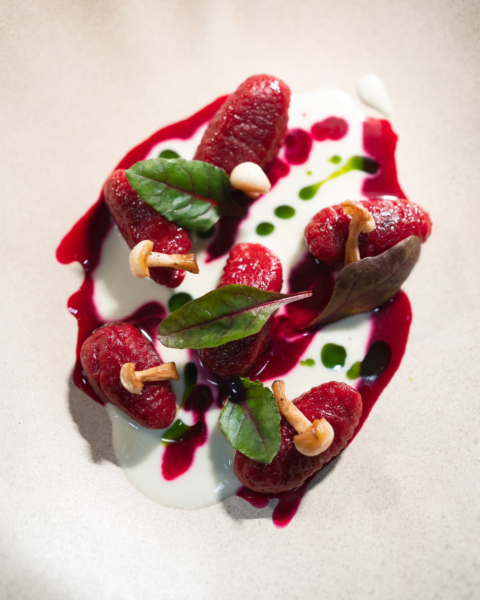 Beetroot gnocchi with sautéed mushrooms, sorrel leaves and a green herb-oil drizzle on a cream sauce.